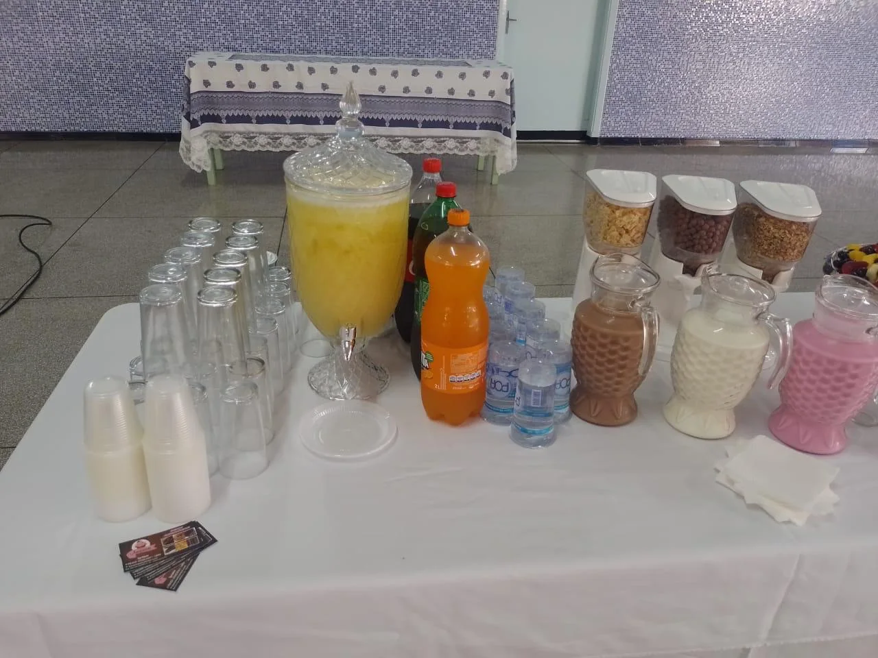 Suco, refrigerante e água servidos em um evento, com copos e cafeteira
