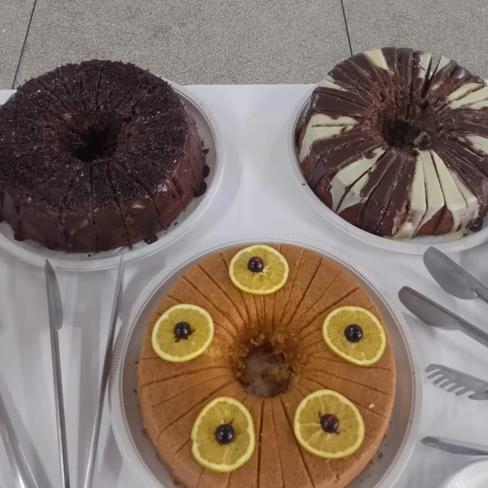 Três bolos caseiros, de chocolate, mesclado e de laranja, servidos em um evento